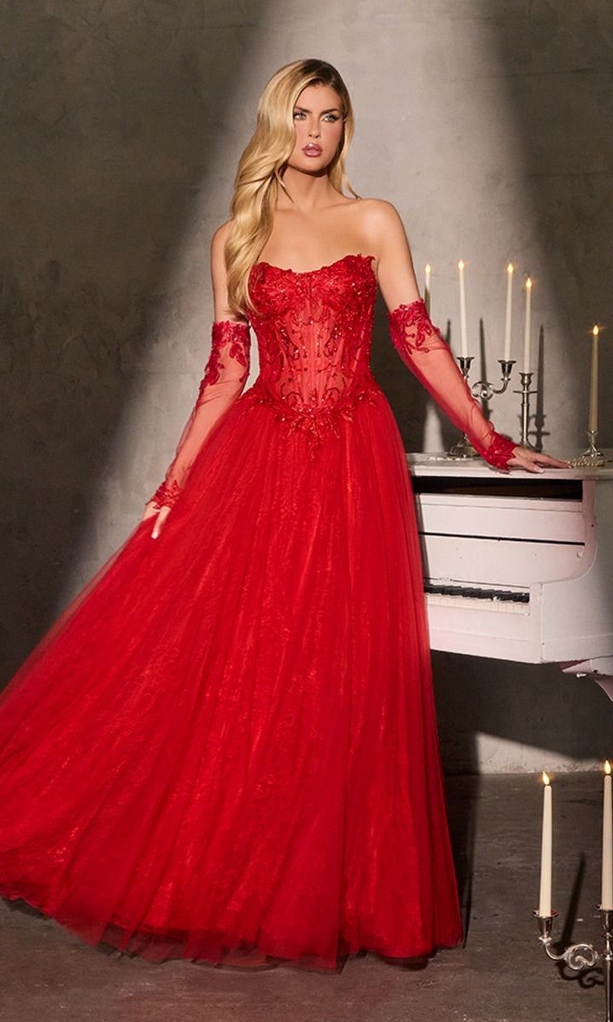 A woman in the Strapless Black Beaded Prom Gown (Ladivine CD717) stands beside a white piano and lit candelabra in a dimly lit room.